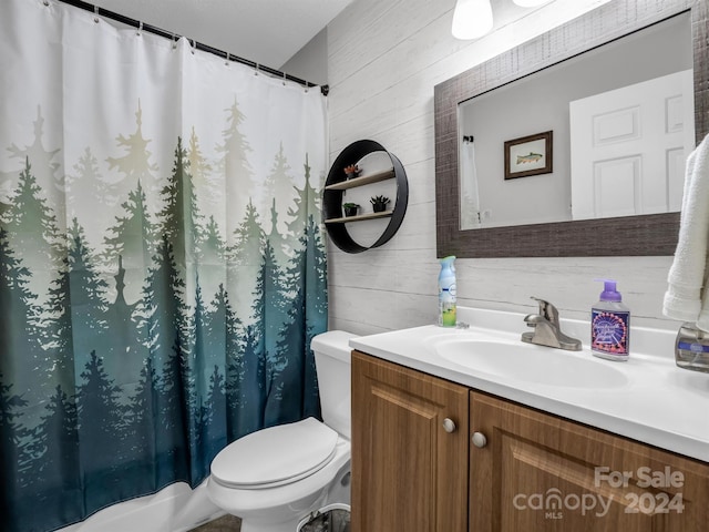 bathroom featuring toilet, vanity, and wooden walls