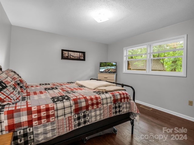 bedroom with a textured ceiling and hardwood / wood-style flooring