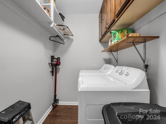 laundry room featuring dark wood-type flooring, separate washer and dryer, a textured ceiling, and cabinets