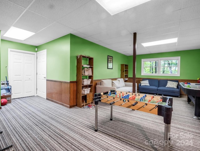 game room featuring carpet, a paneled ceiling, and wooden walls