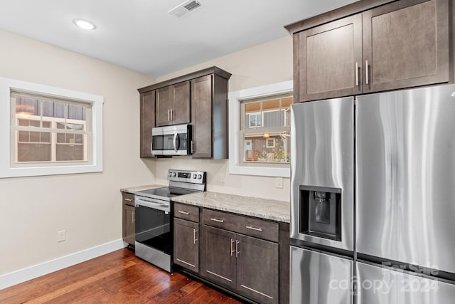 kitchen featuring light stone countertops, stainless steel appliances, dark brown cabinets, and dark hardwood / wood-style flooring