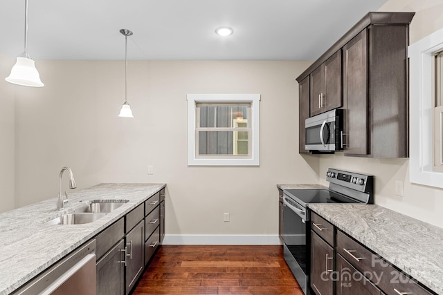 kitchen with dark brown cabinets, stainless steel appliances, dark wood-type flooring, sink, and decorative light fixtures