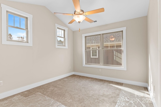 empty room featuring a wealth of natural light, lofted ceiling, light colored carpet, and ceiling fan