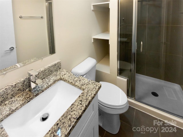 bathroom featuring toilet, vanity, and an enclosed shower