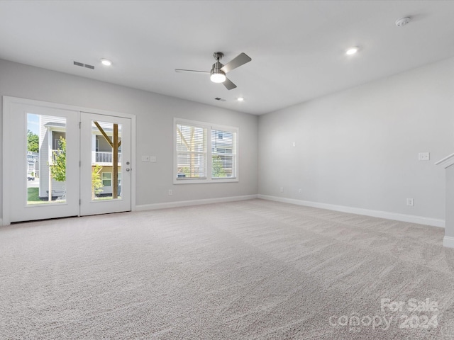 carpeted empty room with ceiling fan and plenty of natural light