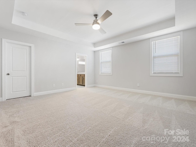 spare room featuring ceiling fan, a raised ceiling, and light colored carpet