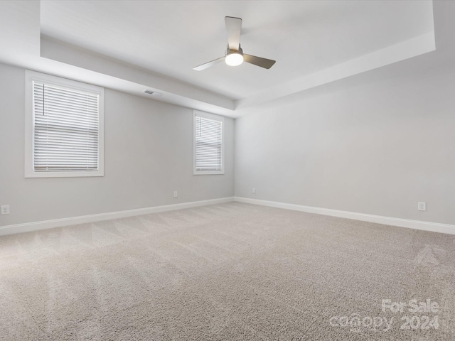 unfurnished room featuring a tray ceiling, ceiling fan, and carpet flooring