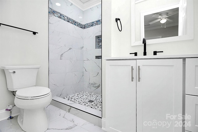 bathroom featuring a tile shower, ceiling fan, toilet, vanity, and ornamental molding