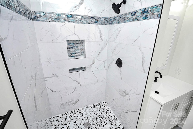 bathroom featuring a tile shower and sink