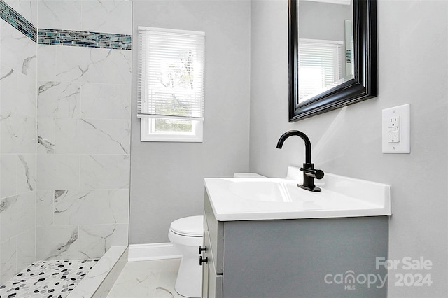 bathroom featuring vanity, toilet, and a tile shower