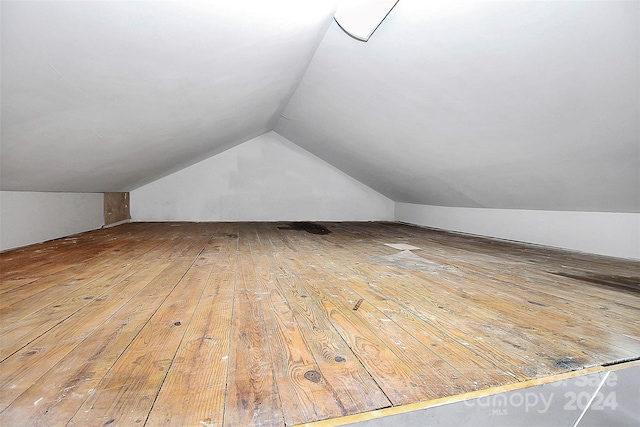 additional living space with hardwood / wood-style floors and lofted ceiling