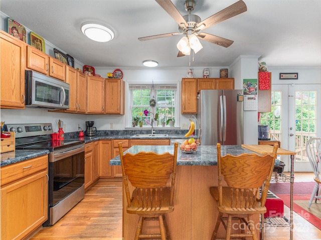 kitchen featuring a kitchen island, stainless steel appliances, light hardwood / wood-style floors, a kitchen breakfast bar, and sink