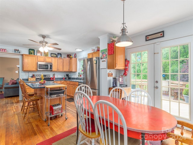 dining room with a healthy amount of sunlight, crown molding, and light hardwood / wood-style flooring