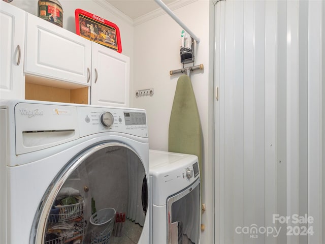 laundry room featuring washing machine and dryer, ornamental molding, and cabinets