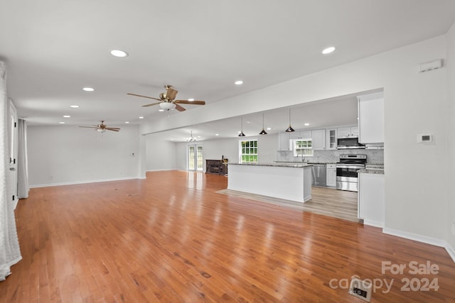 unfurnished living room featuring ceiling fan, sink, and light wood-type flooring