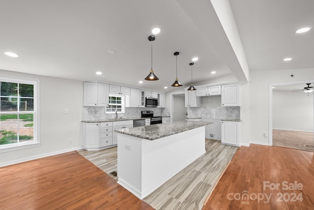 kitchen with appliances with stainless steel finishes, stone countertops, decorative light fixtures, white cabinets, and a center island