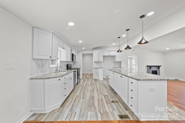 kitchen featuring white cabinetry, sink, hanging light fixtures, stainless steel appliances, and a kitchen island