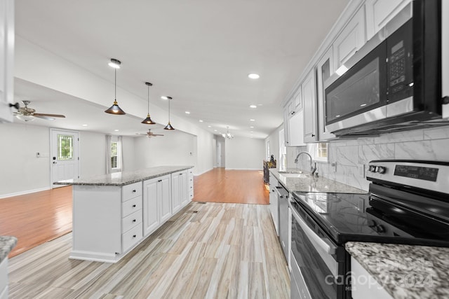 kitchen featuring hanging light fixtures, sink, appliances with stainless steel finishes, light stone counters, and white cabinetry