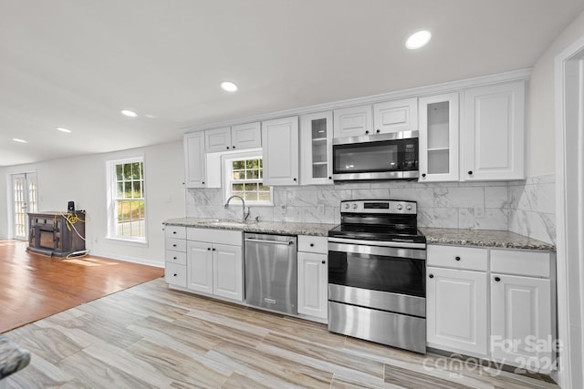 kitchen featuring white cabinetry, sink, light stone counters, and appliances with stainless steel finishes