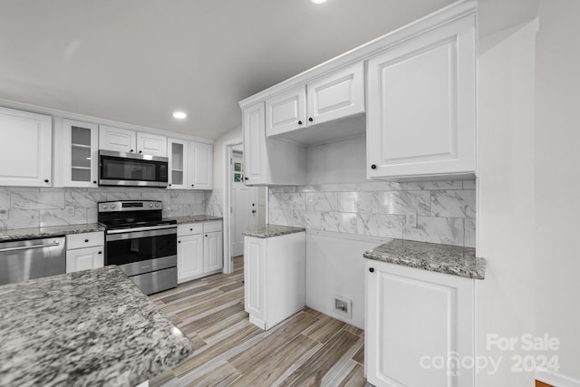 kitchen with light stone counters, white cabinetry, and appliances with stainless steel finishes