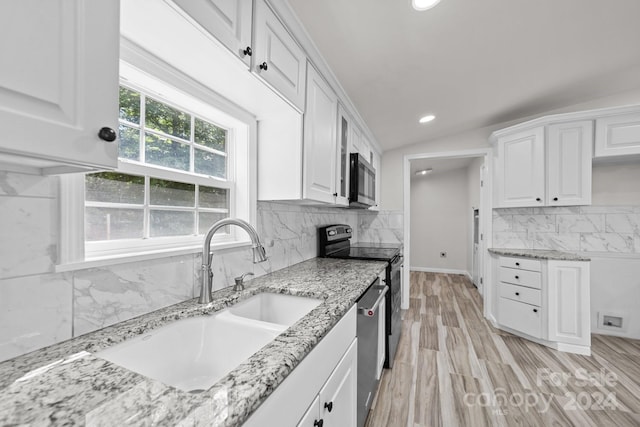 kitchen featuring white cabinets, appliances with stainless steel finishes, light stone counters, and sink