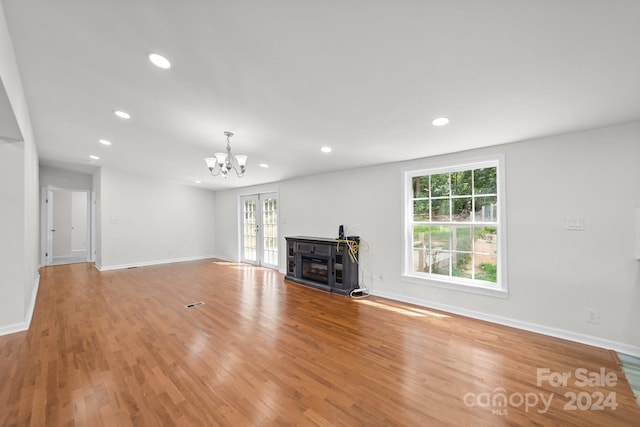 unfurnished living room featuring a fireplace, light hardwood / wood-style flooring, and an inviting chandelier