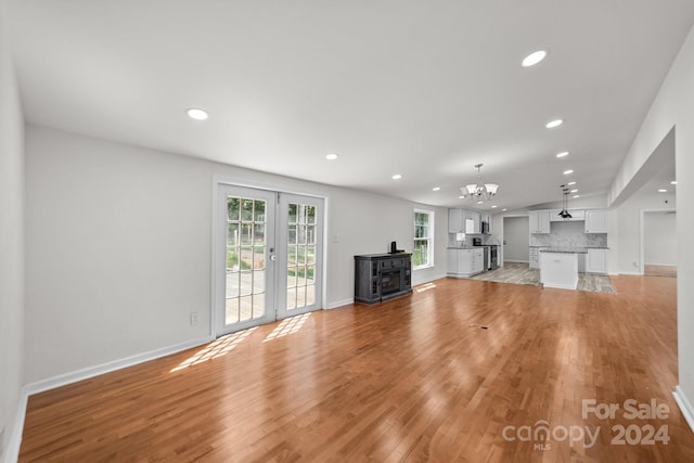 unfurnished living room featuring a chandelier, french doors, and light hardwood / wood-style flooring