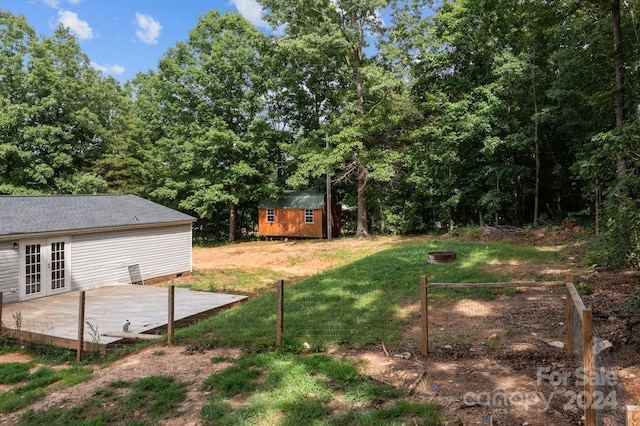 view of yard with french doors, a deck, and a storage shed