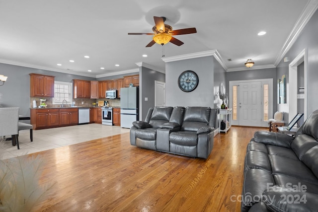 living room with crown molding, light wood-type flooring, and sink