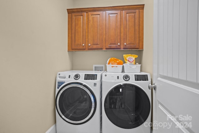 washroom with washer and dryer and cabinets