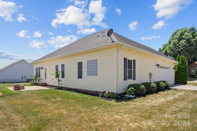 view of side of home with a lawn, a garage, and an outdoor fire pit