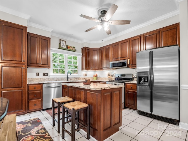 kitchen featuring ornamental molding, light tile patterned floors, a center island, and stainless steel appliances