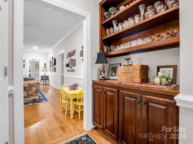 bar featuring ornamental molding and light hardwood / wood-style flooring