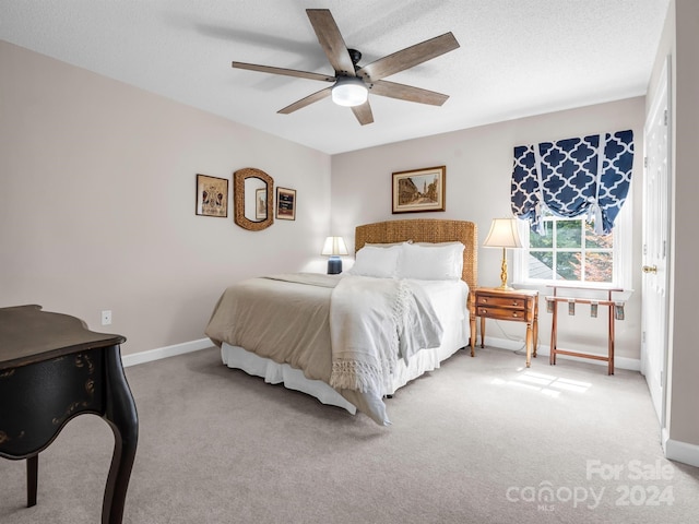 bedroom featuring ceiling fan, light colored carpet, and a textured ceiling