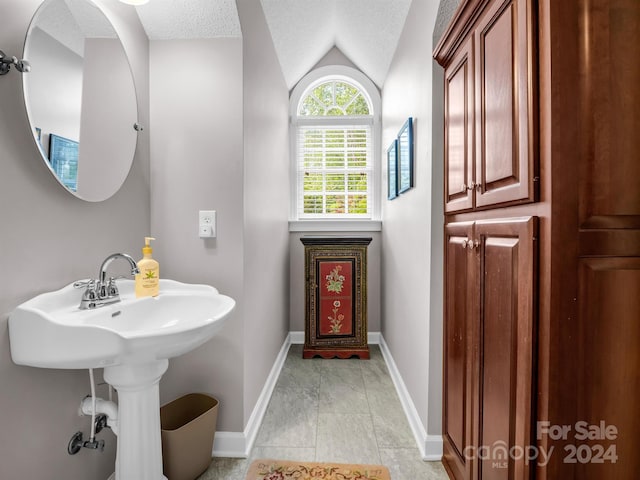 bathroom featuring a textured ceiling, tile patterned floors, and lofted ceiling