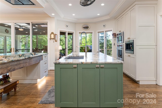 kitchen featuring white cabinetry, light stone countertops, green cabinets, dark hardwood / wood-style floors, and an island with sink