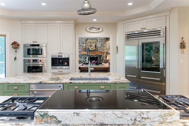 kitchen featuring white cabinets, green cabinets, appliances with stainless steel finishes, and a tray ceiling