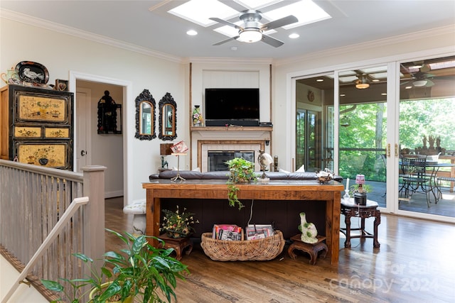 living room with wood-type flooring, ornamental molding, and a tiled fireplace