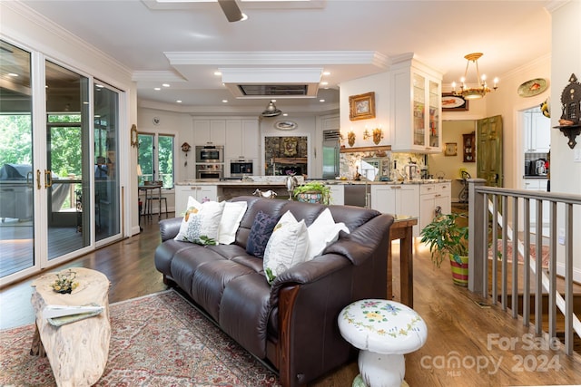 living room featuring ceiling fan with notable chandelier, wood-type flooring, and crown molding