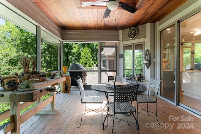 sunroom / solarium with a healthy amount of sunlight, ceiling fan, and wooden ceiling