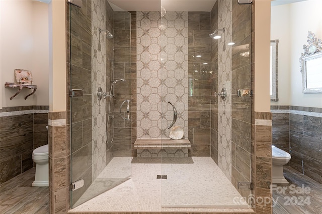 bathroom featuring a shower with door, tile patterned flooring, tile walls, and toilet