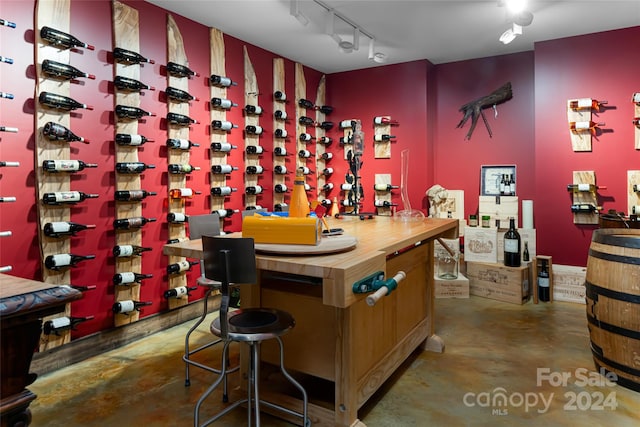 wine area featuring concrete flooring and track lighting