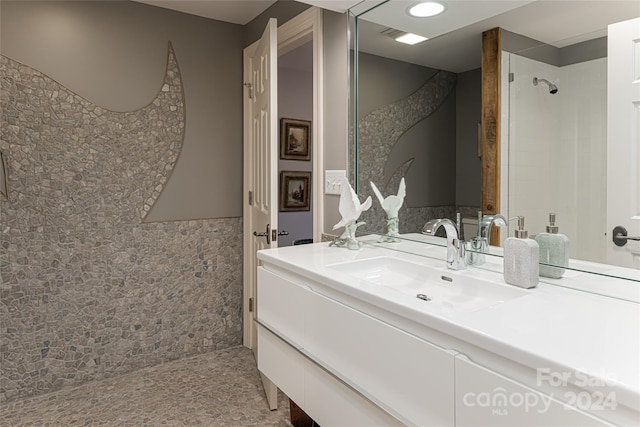 bathroom with a tile shower and vanity