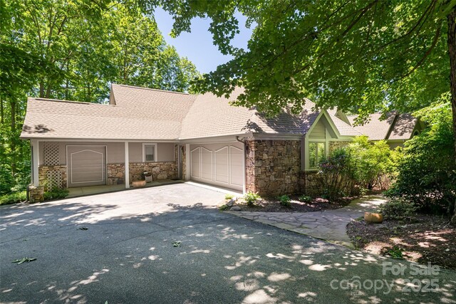 57 Old Hickory Trl, Hendersonville, NC 28739 - view of front of home with stone siding, driveway, an attached garage, and a shingled roof