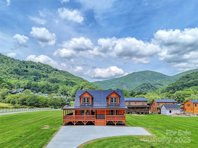 view of front of property featuring a deck with mountain view, metal roof, a standing seam roof, and a front lawn