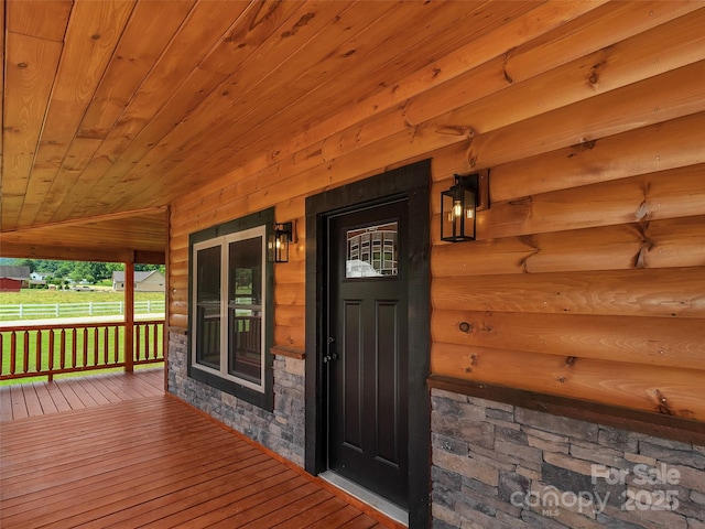 doorway to property with a porch and stone siding