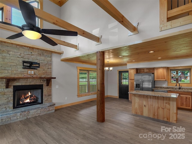 kitchen featuring stainless steel fridge, open floor plan, a kitchen island, a sink, and wood finished floors