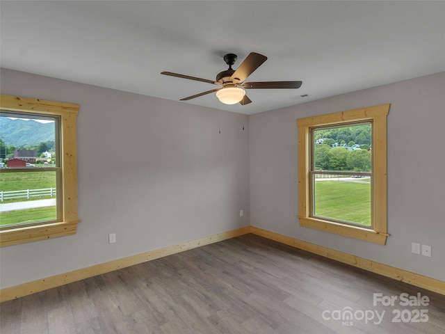 empty room with baseboards, wood finished floors, and a healthy amount of sunlight