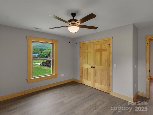 unfurnished bedroom with wood finished floors, baseboards, and visible vents