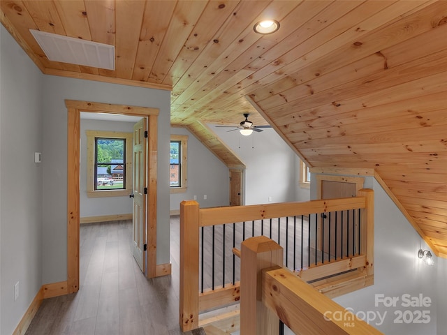 hall featuring wooden ceiling, wood finished floors, baseboards, and an upstairs landing